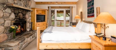 A bedroom with a stone fireplace, wooden bed, and a view of the outdoors through a sliding door.