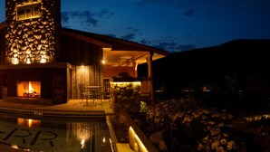A lodge with a stone fireplace, outdoor seating, and a swimming pool. - Rainbow Ranch Lodge (Gallatin Gateway)