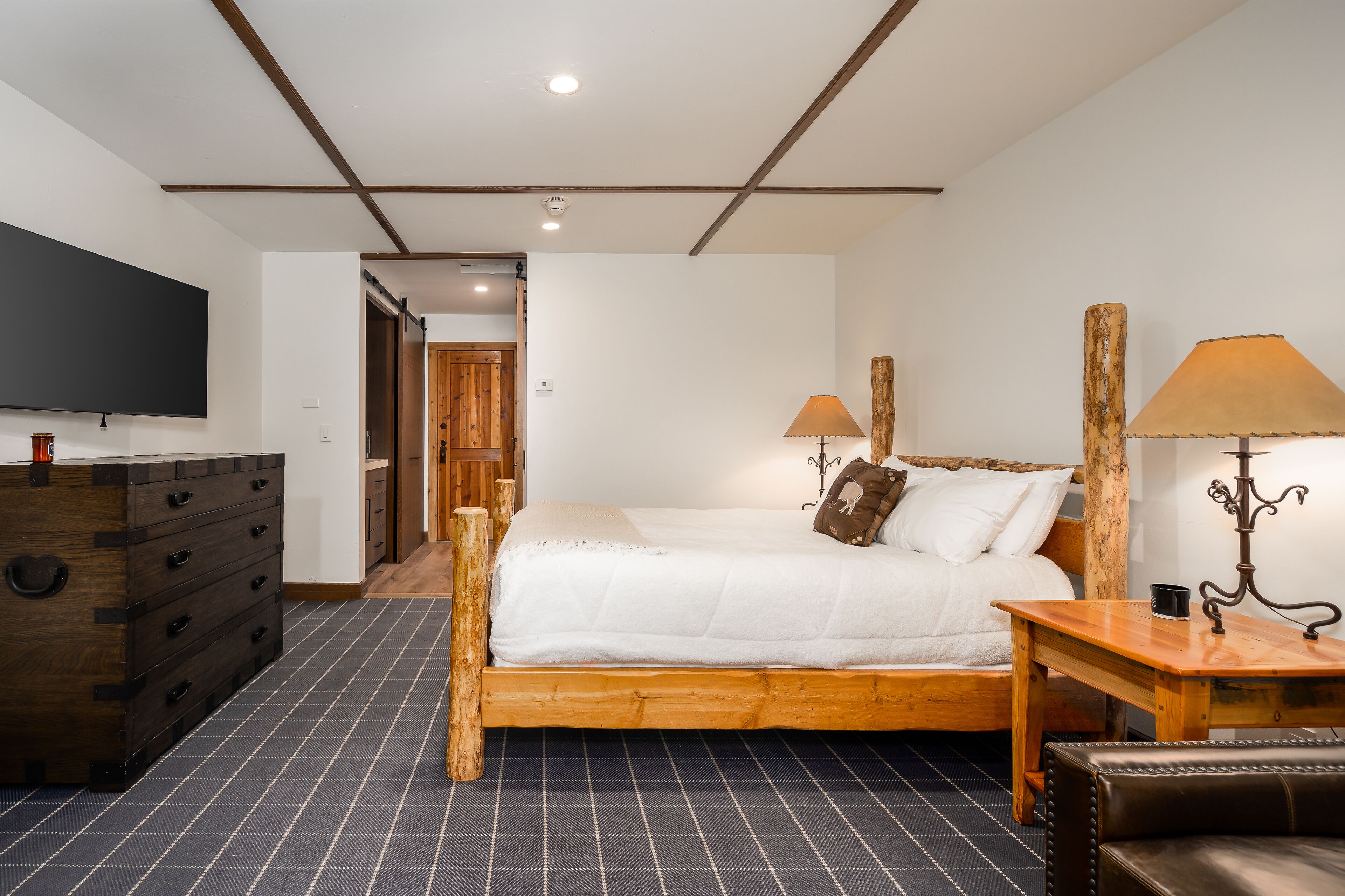 Une chambre à coucher avec un lit en bois, une commode, un téléviseur et une lampe.