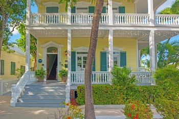 A dining area with a table, two chairs, and a floral centerpiece. at Silver Palms Inn & Historic Homes