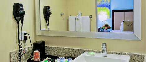 A hotel bathroom with a sink, hair dryer, and towel rack.