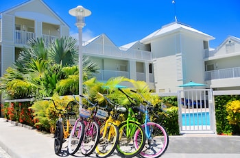 A two-story yellow house with a porch, white railings, and green shutters. at Silver Palms Inn & Historic Homes