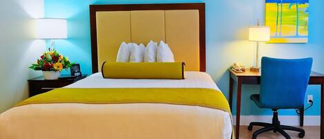 A hotel room with a large bed, a desk with a chair, a lamp, and a painting on the wall.