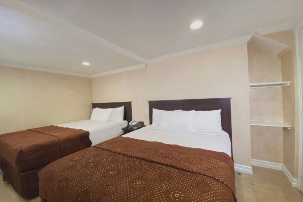 A hotel room with two beds, a nightstand, and a built-in shelf.