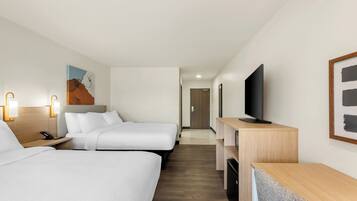 A hotel room with two beds, a desk, a television, and a painting on the wall.