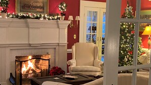 A cozy living room with a fireplace, a comfortable armchair, and a Christmas tree. - A Williamsburg White House (Williamsburg)