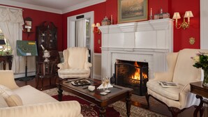 A living room with a fireplace, red walls, and cream-colored furniture. - A Williamsburg White House (Williamsburg)