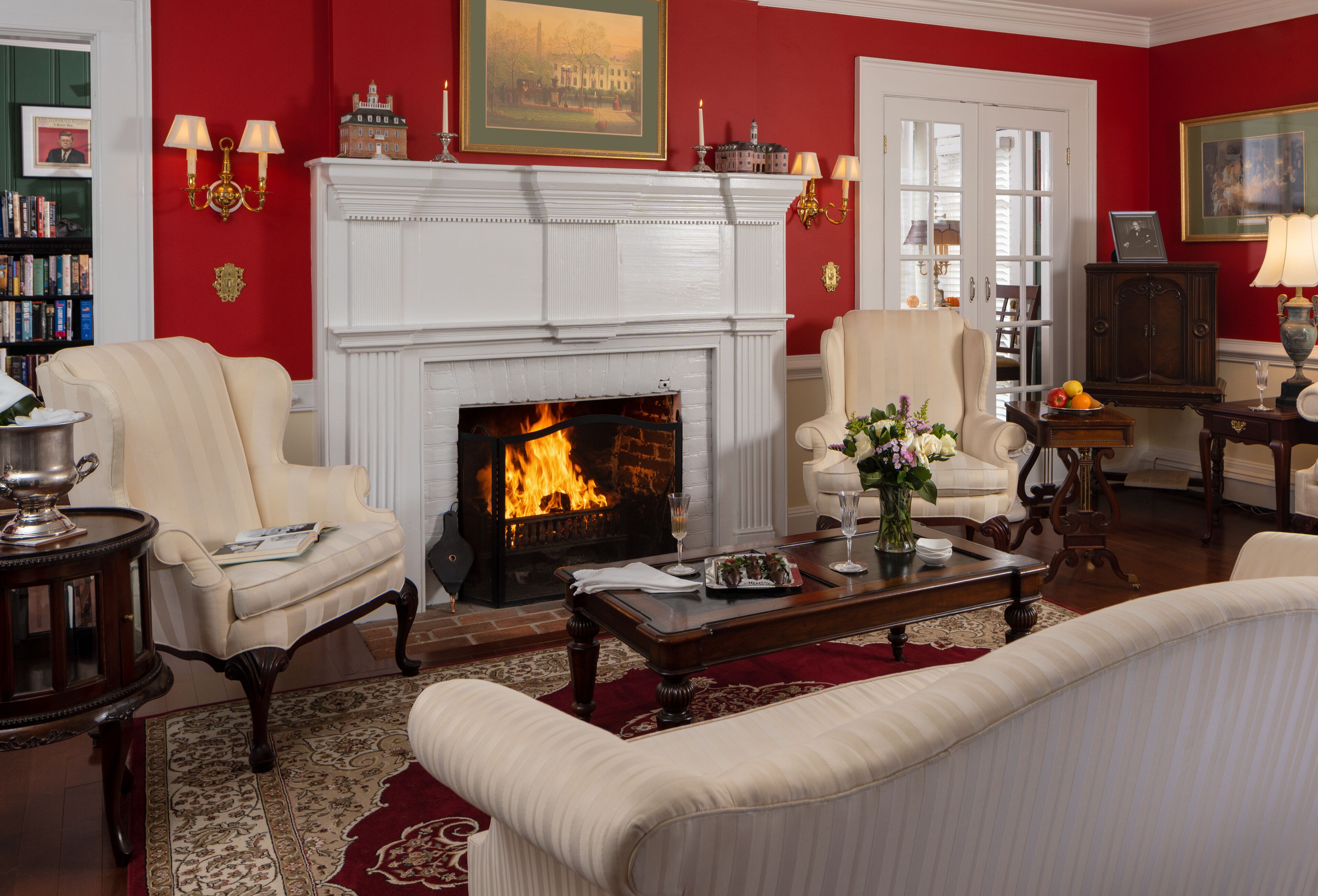 A room with a fireplace, two armchairs, a sofa, a coffee table, and a bookshelf.