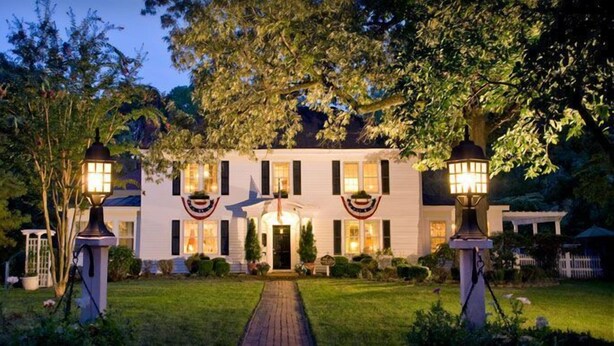 A large, white house with a central entrance, flanked by two large trees and two street lamps. - A Williamsburg White House (Williamsburg)