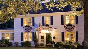 Ein weißes Gebäude mit dunklen Fensterläden, eine amerikanische Flagge und ein Schild mit der Aufschrift 'White House Inn'.