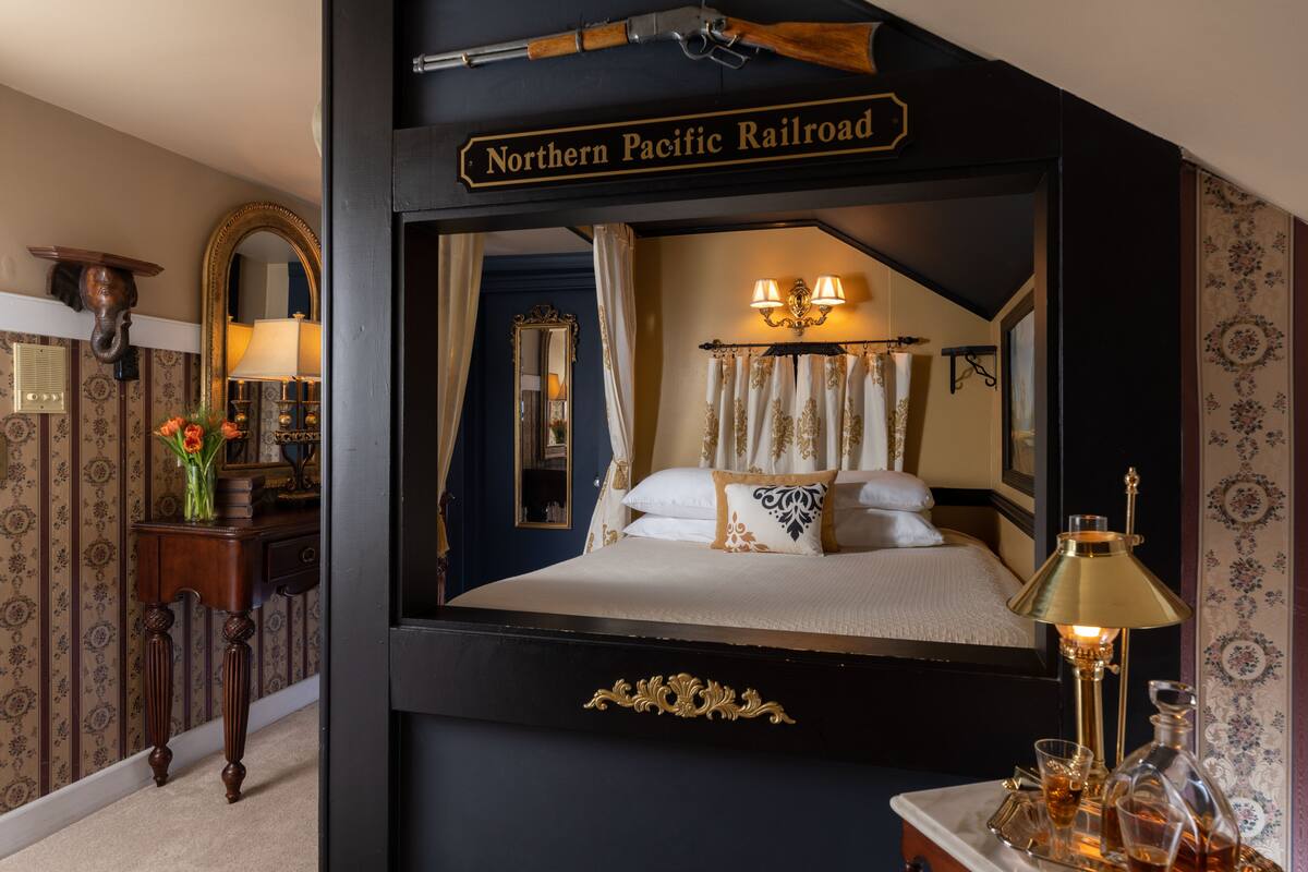 Una habitación con una cama grande, un espejo, un aparador y un cartel que dice 'Northern Pacific Railroad'.