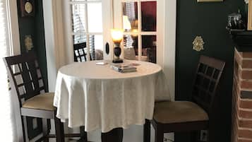 Un comedor con una mesa redonda, dos sillas, una lámpara y una estantería al fondo.