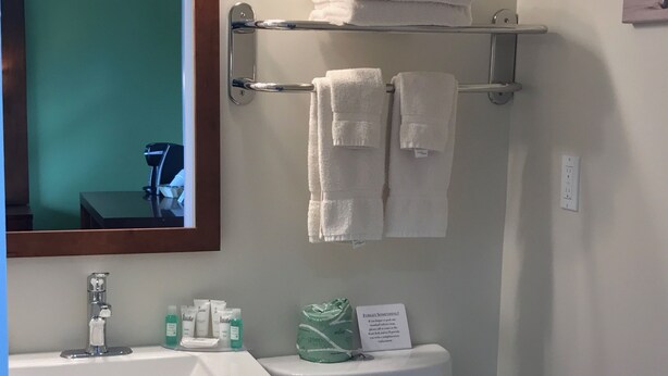 A bathroom with a sink, mirror, towel rack, toilet, and storage cabinets. - Ledges by the Bay (Rockport)