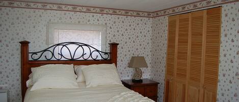 Una camera da letto con un letto in legno, un comodino, una lampada, una finestra e un'armadio in legno.