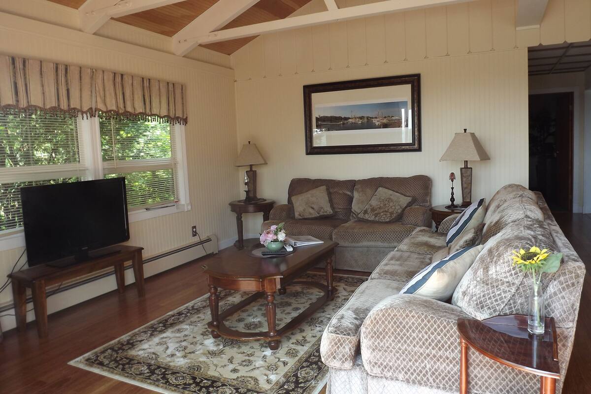 A living room with a sofa, a coffee table, a television, and a framed picture on the wall.