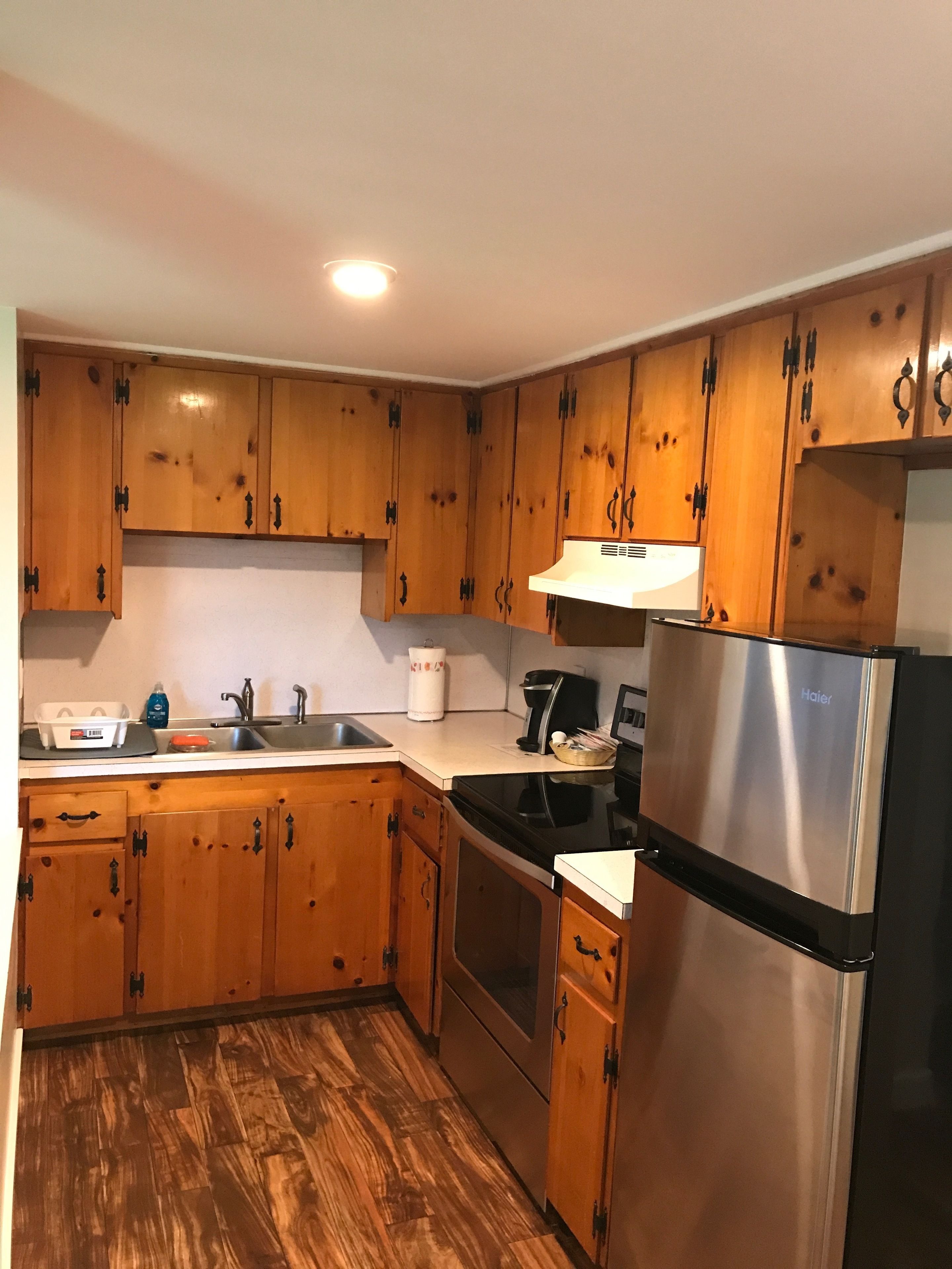 A kitchen with wooden cabinets, a stainless steel refrigerator, a stove, and a sink.