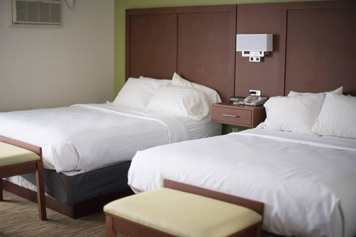 Two single beds with white linens, wooden headboards, and bedside tables with lamps.