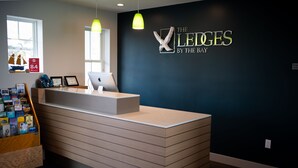 Un comptoir d’accueil avec un mur sombre et une enseigne indiquant : « The XLEGES by the Bay ».