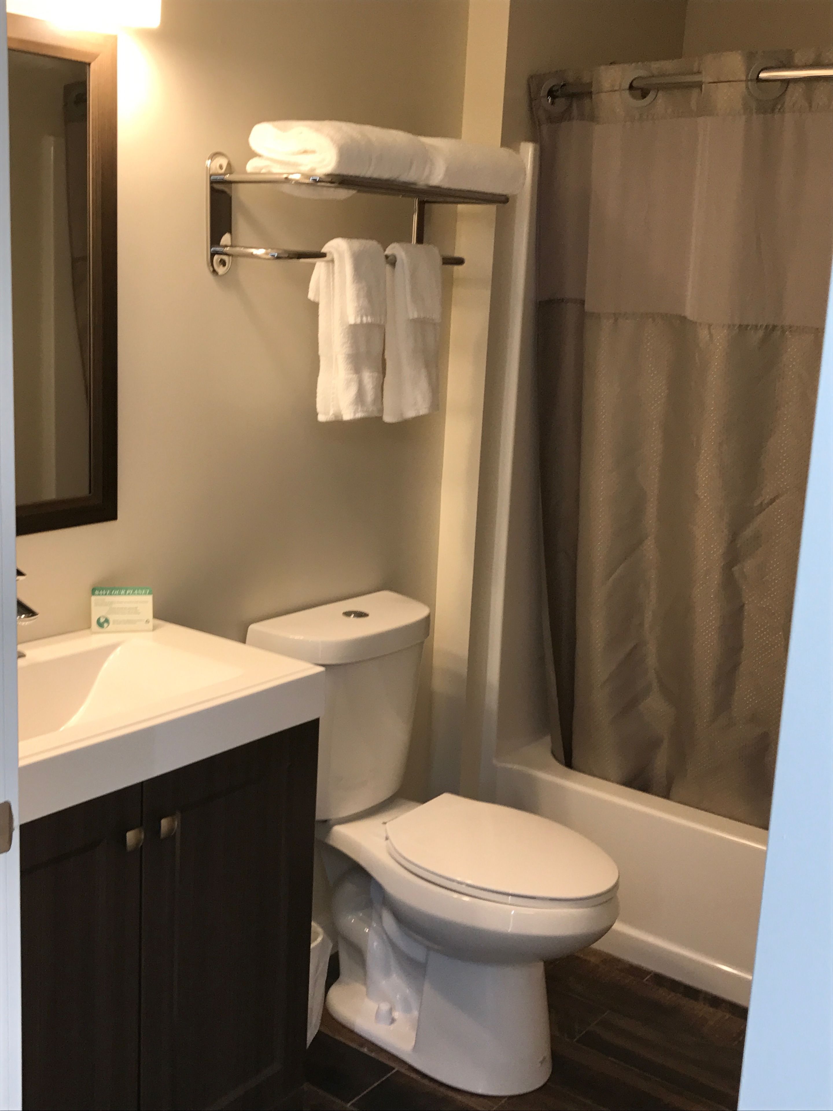 Un baño moderno con inodoro blanco, lavamanos y cortina de ducha.