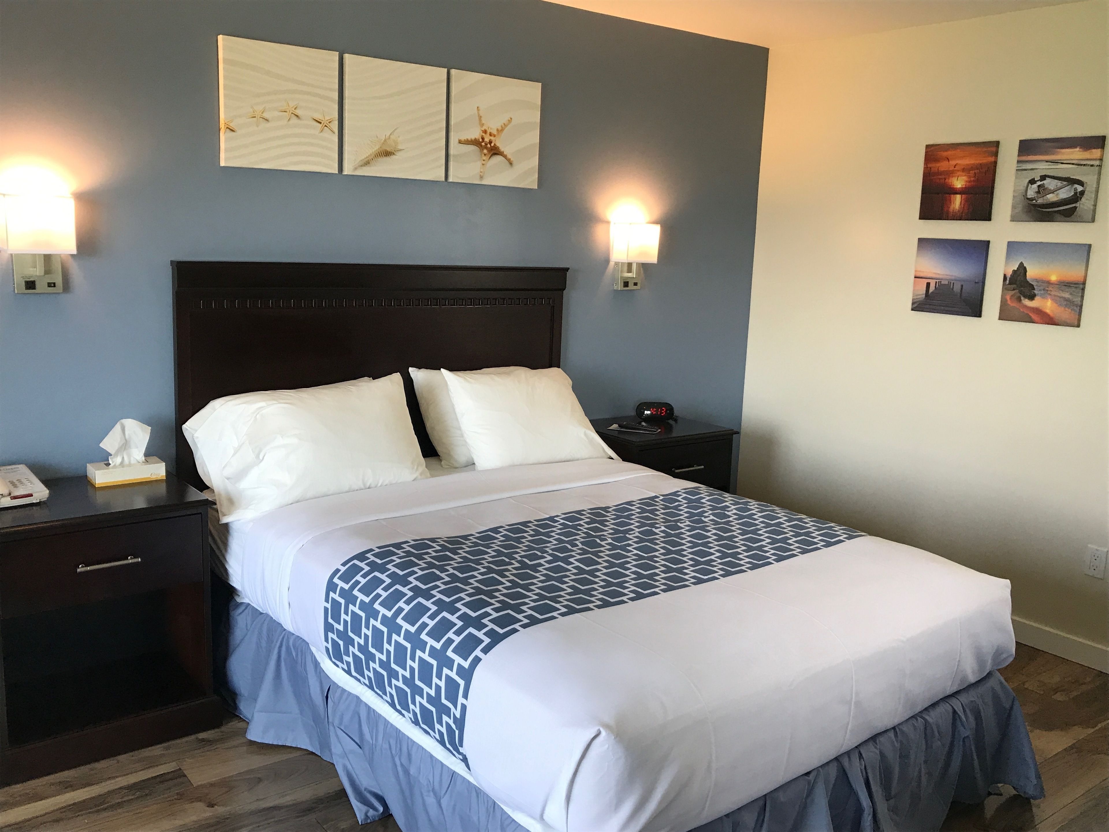 A neatly made bed with a patterned bedspread, a headboard, and two bedside lamps.