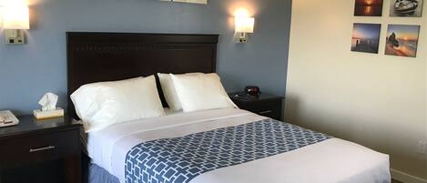 A neatly made bed with a patterned bedspread, a headboard, and two bedside lamps.