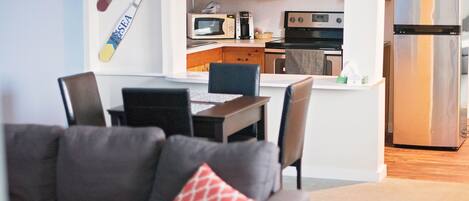 A modern kitchen with wooden cabinets, a microwave, a coffee maker, and a stainless steel refrigerator.