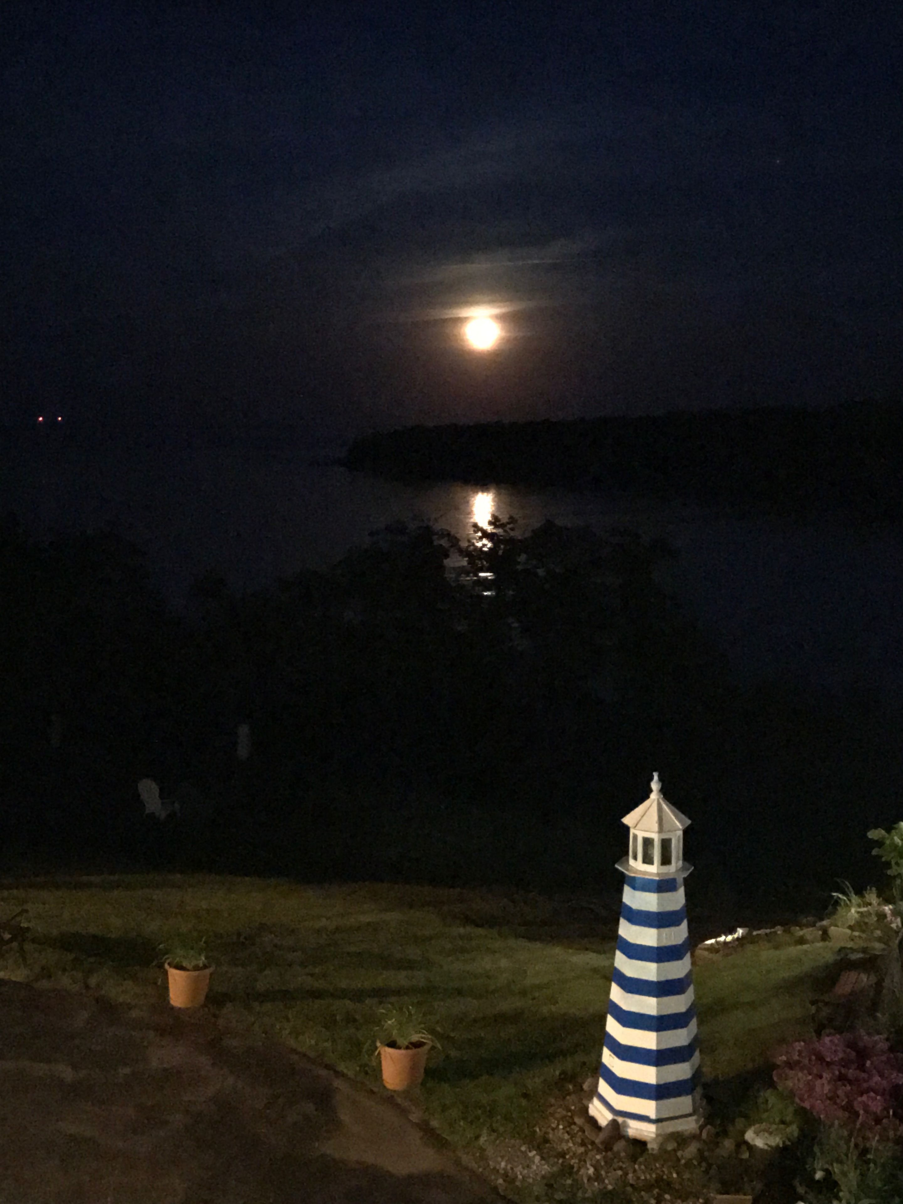 A lighthouse at night with a full moon in the background.
