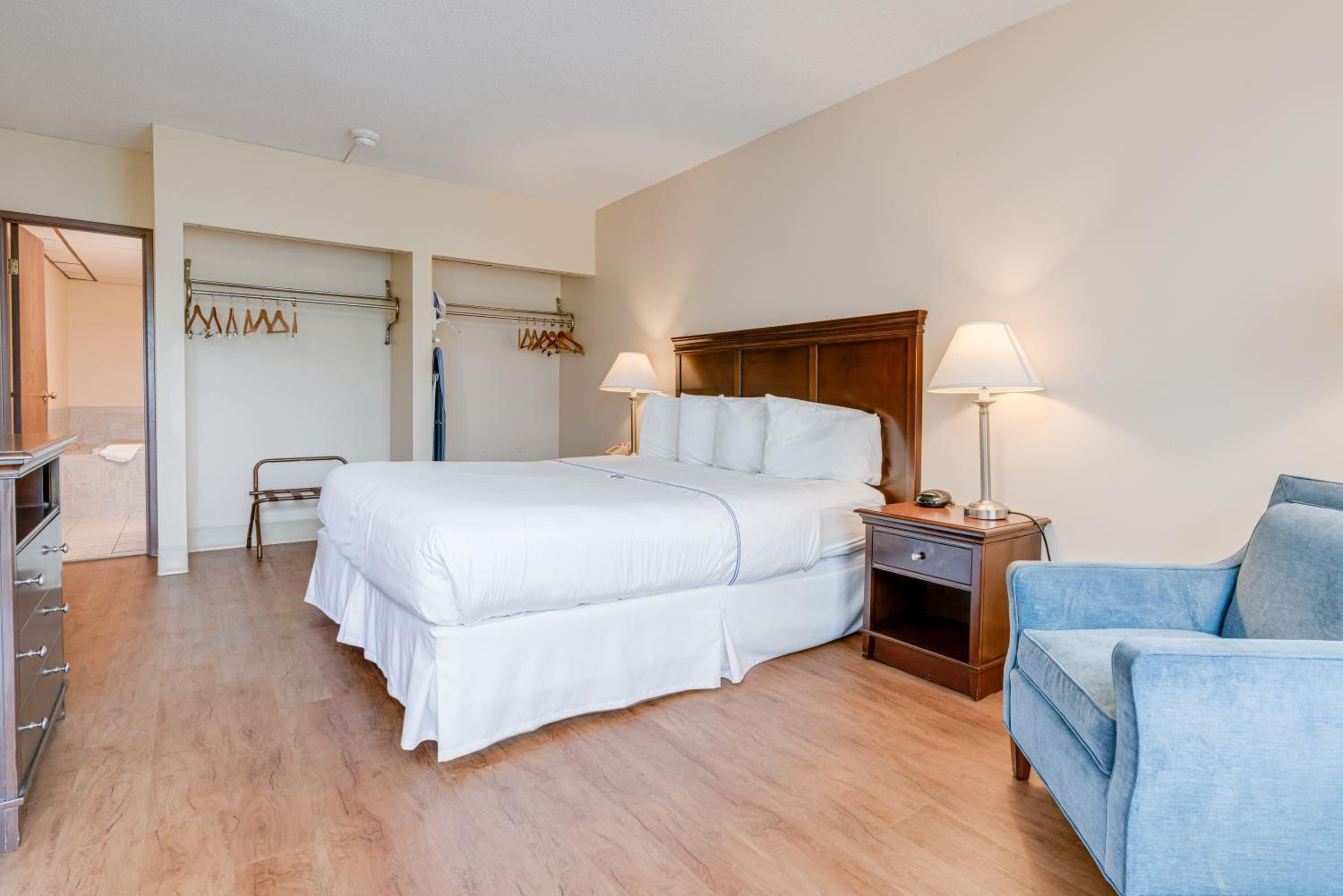 Ein Hotelzimmer mit einem großen Bett, Nachttischen, einem Sessel und einem Kleiderschrank.