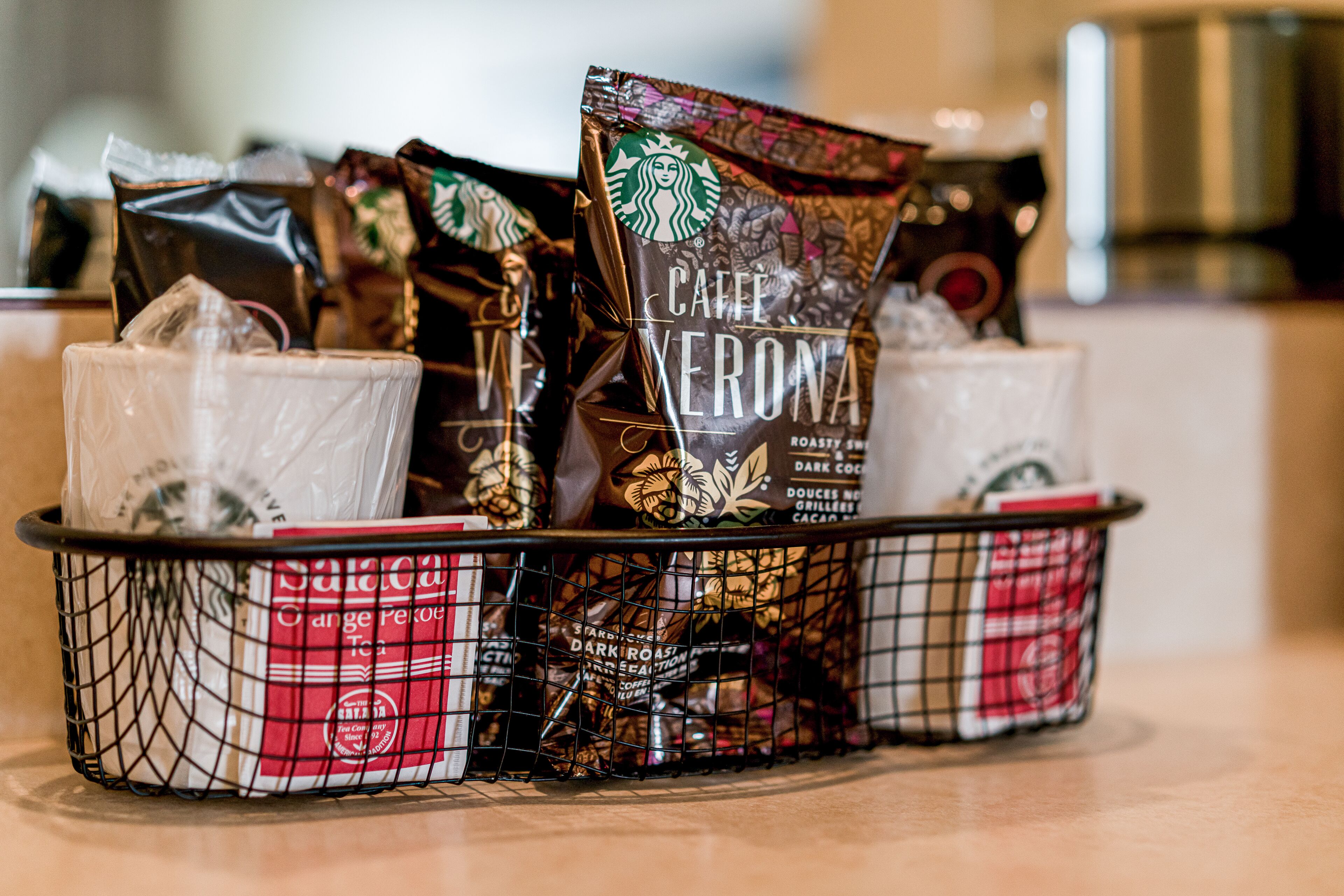 Ein Korb mit verschiedenen Starbucks Kaffeebeuteln und Einwegbechern.