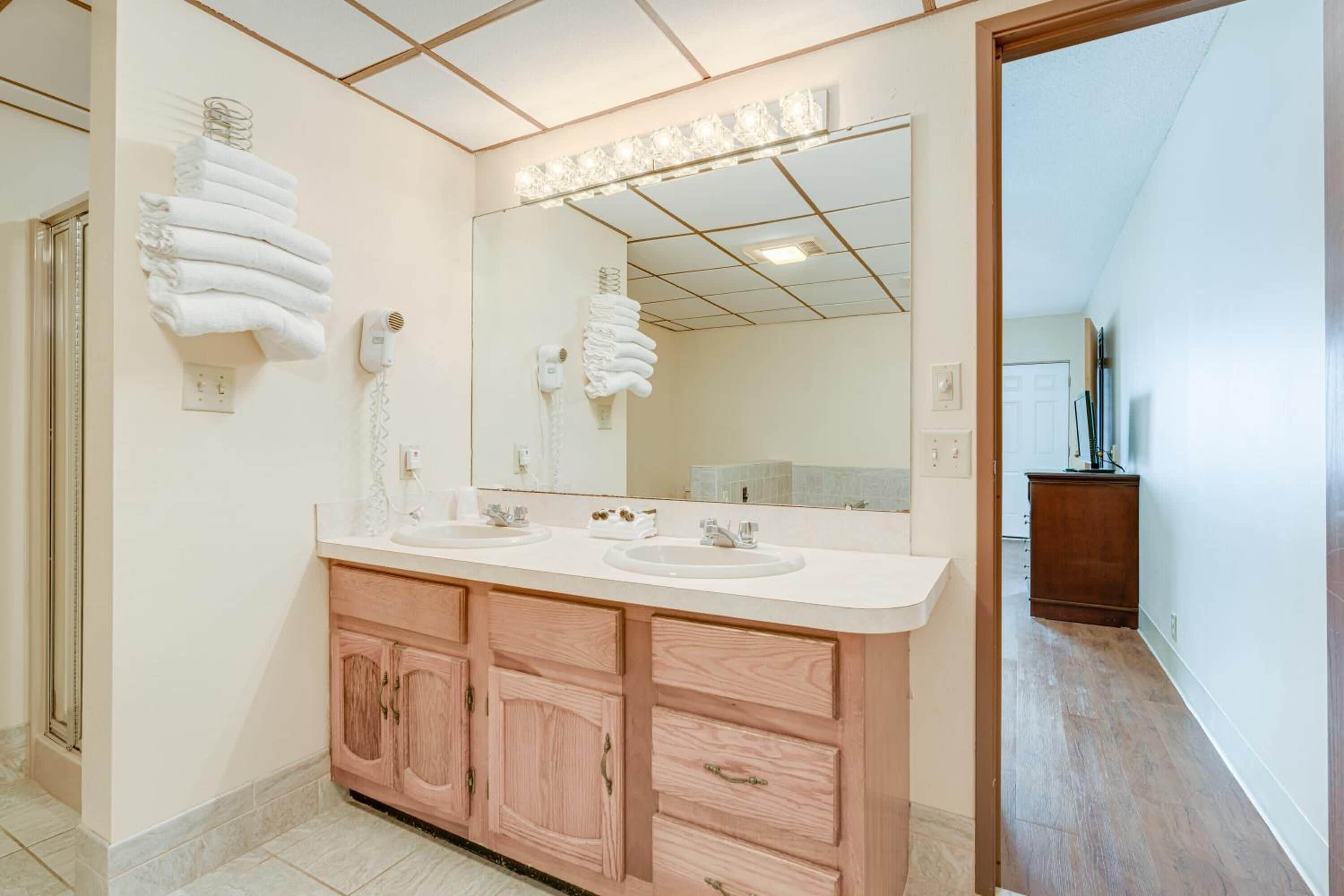 A modern bathroom with two sinks, a large mirror, and wooden cabinets.