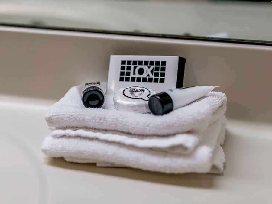 A stack of white towels with a bottle of lotion and a bottle of shampoo on top.