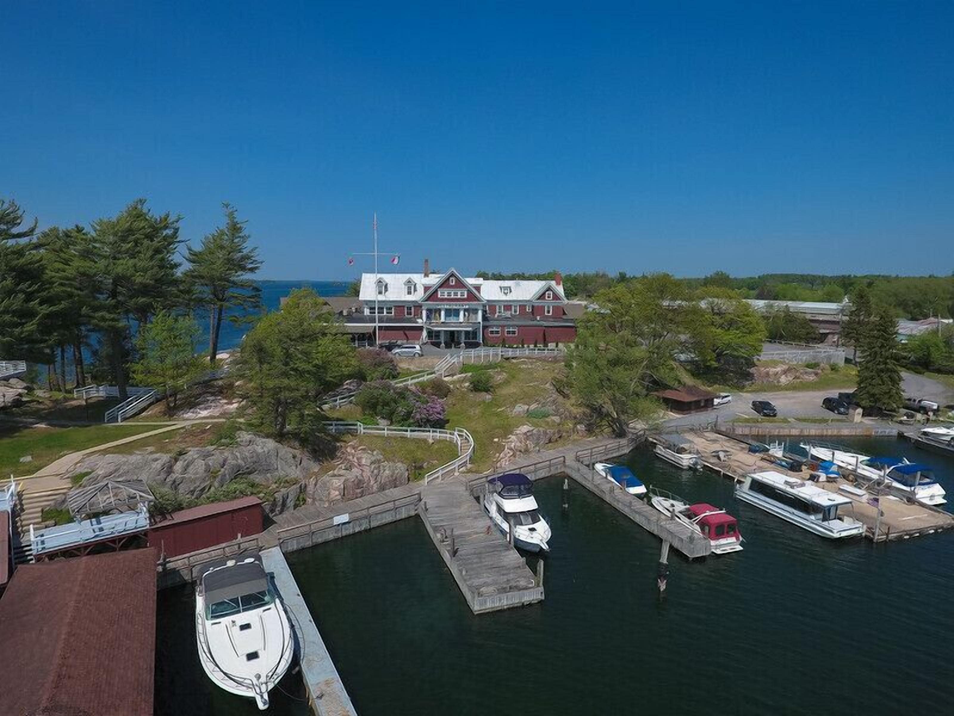 A waterfront property with a large house, docked boats, and a clear view of the water.