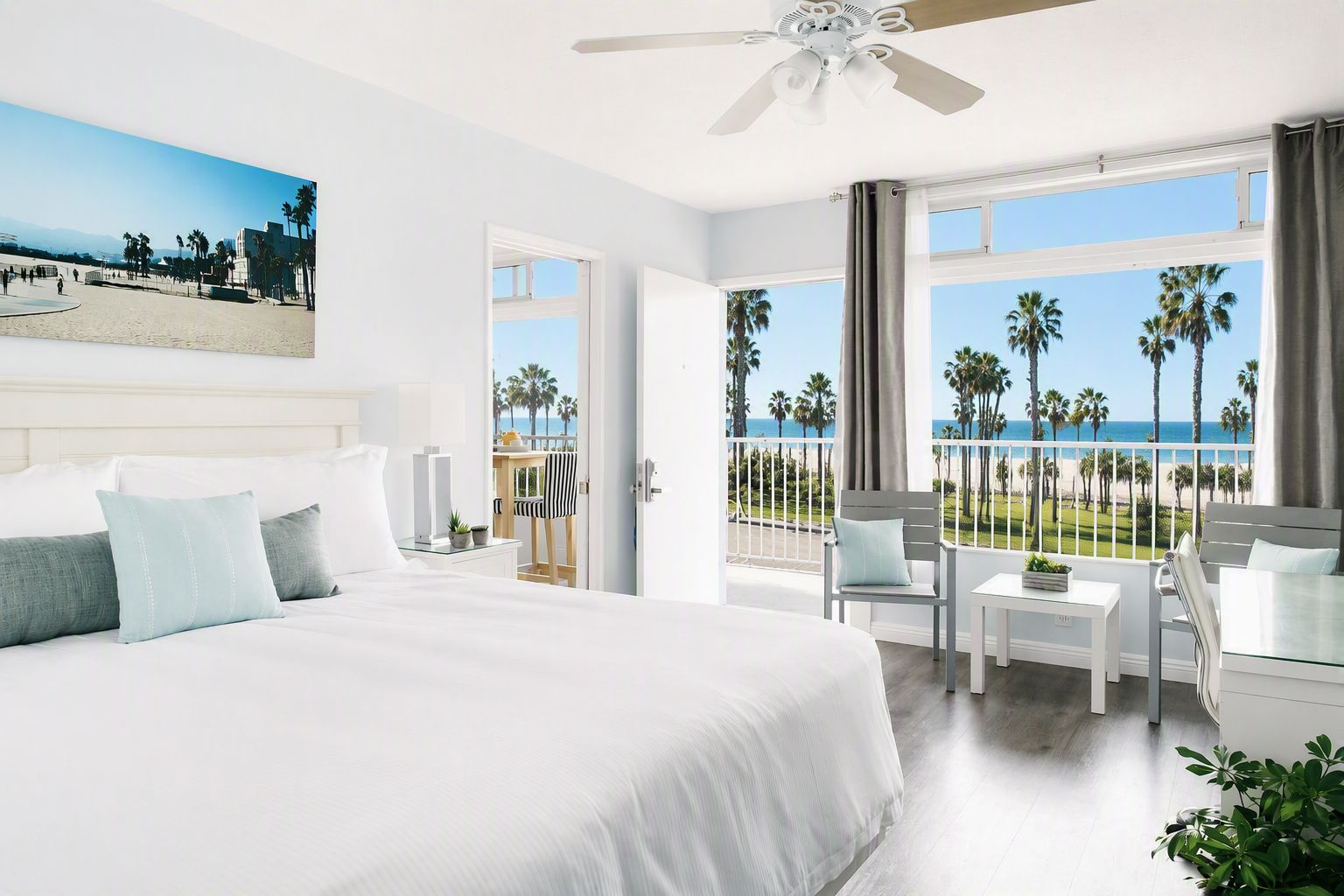 Ein Hotelzimmer mit einem großen Bett, einem Balkon mit Blick auf den Strand und einem Deckenventilator.