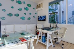 A modern office with a glass desk, white cabinets, and a wall decorated with fish decals. - Bayside Hotel (Santa Monica)