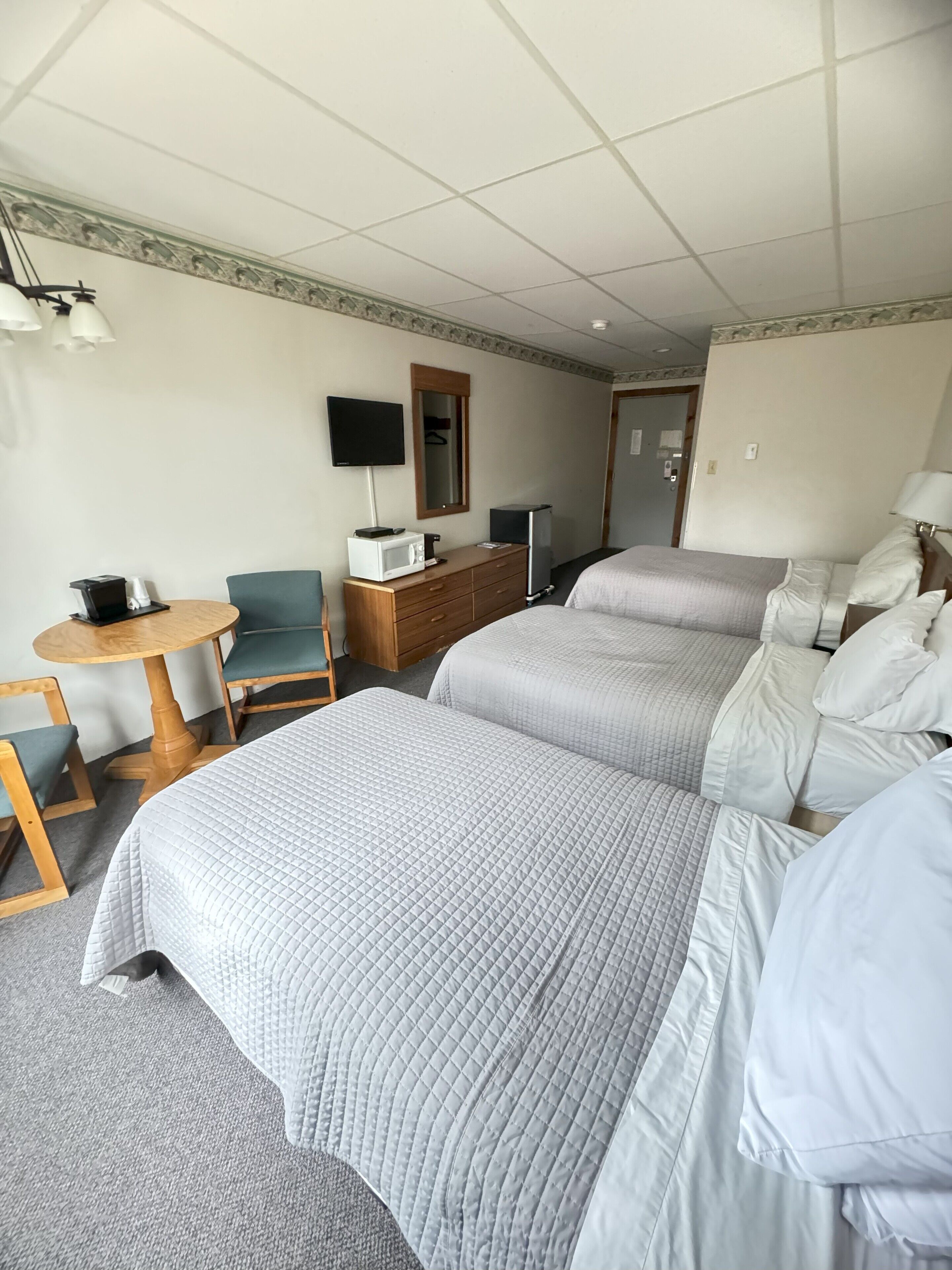 A hotel room with two beds, a desk with a computer, a chair, a TV, and a dresser.