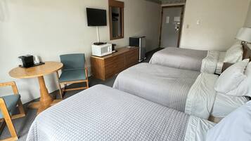 A hotel room with two beds, a desk with a computer, a chair, a TV, and a dresser.