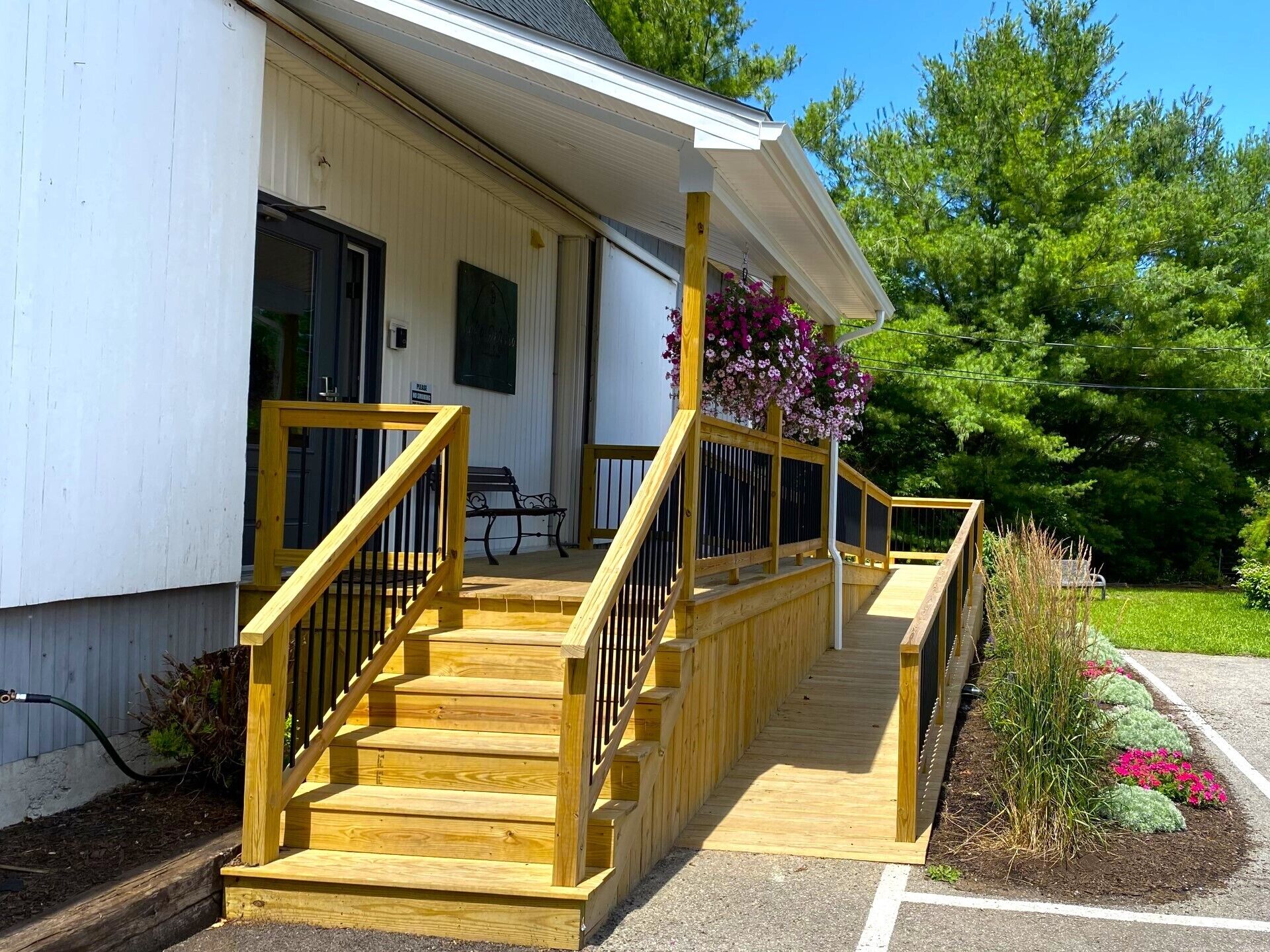 A wooden staircase leading to a porch with a bench and flower baskets.