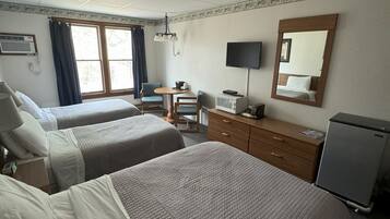Quarto de hotel com duas camas, uma escrivaninha, televisão, espelho e frigorífico.