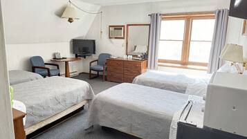 Habitación de hotel con dos camas, un escritorio, una silla, un aparador, un televisor y una ventana con cortinas.