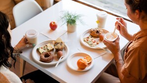 Una mesa de comedor con platos de comida, una taza de café y una planta.