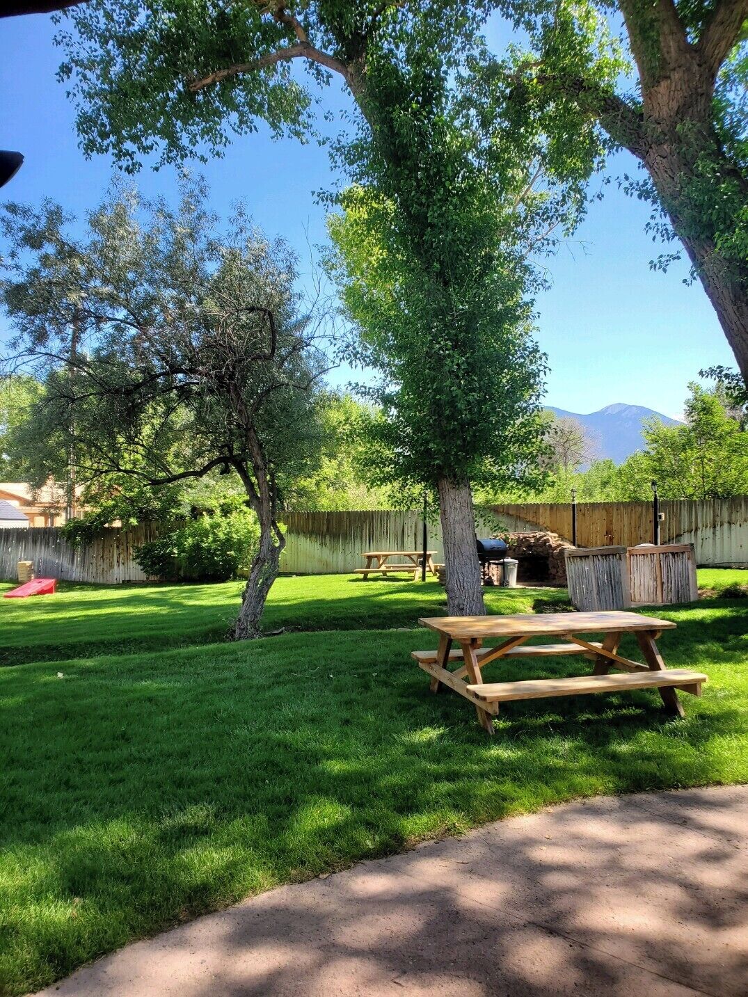 Un patio trasero con una mesa de picnic, una parrilla y una valla de madera.