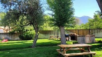 Un patio trasero con una mesa de picnic, una parrilla y una valla de madera.