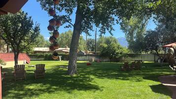 Un patio trasero con un árbol, sillas y una sombrilla roja.