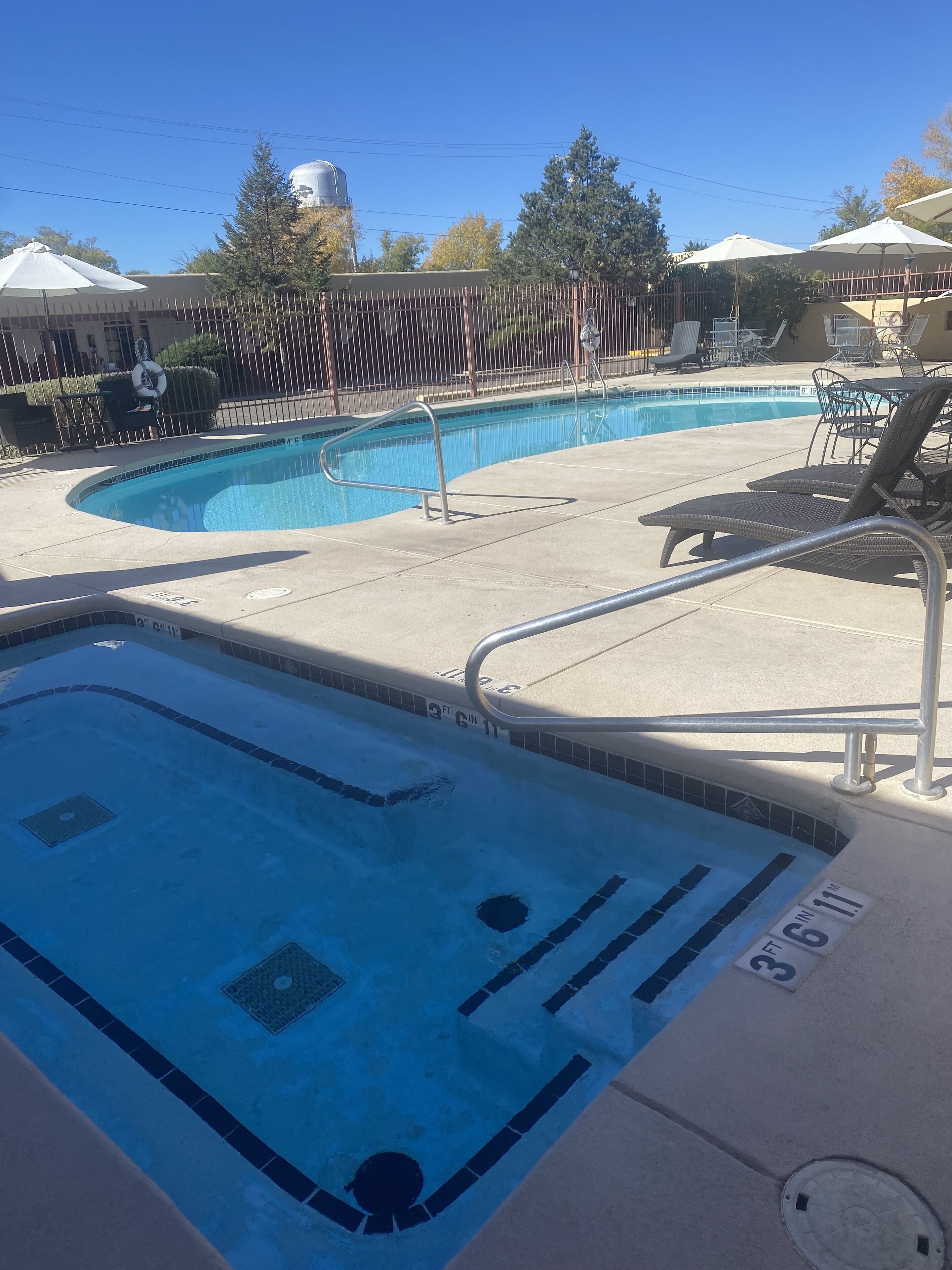 A swimming pool with a metal ladder and lounge chairs.