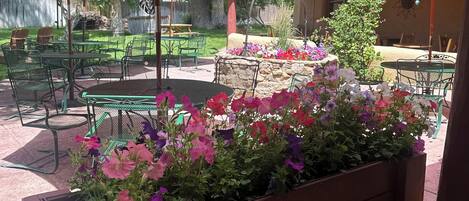 A patio area with outdoor seating, a fire pit, and a planter with colorful flowers.