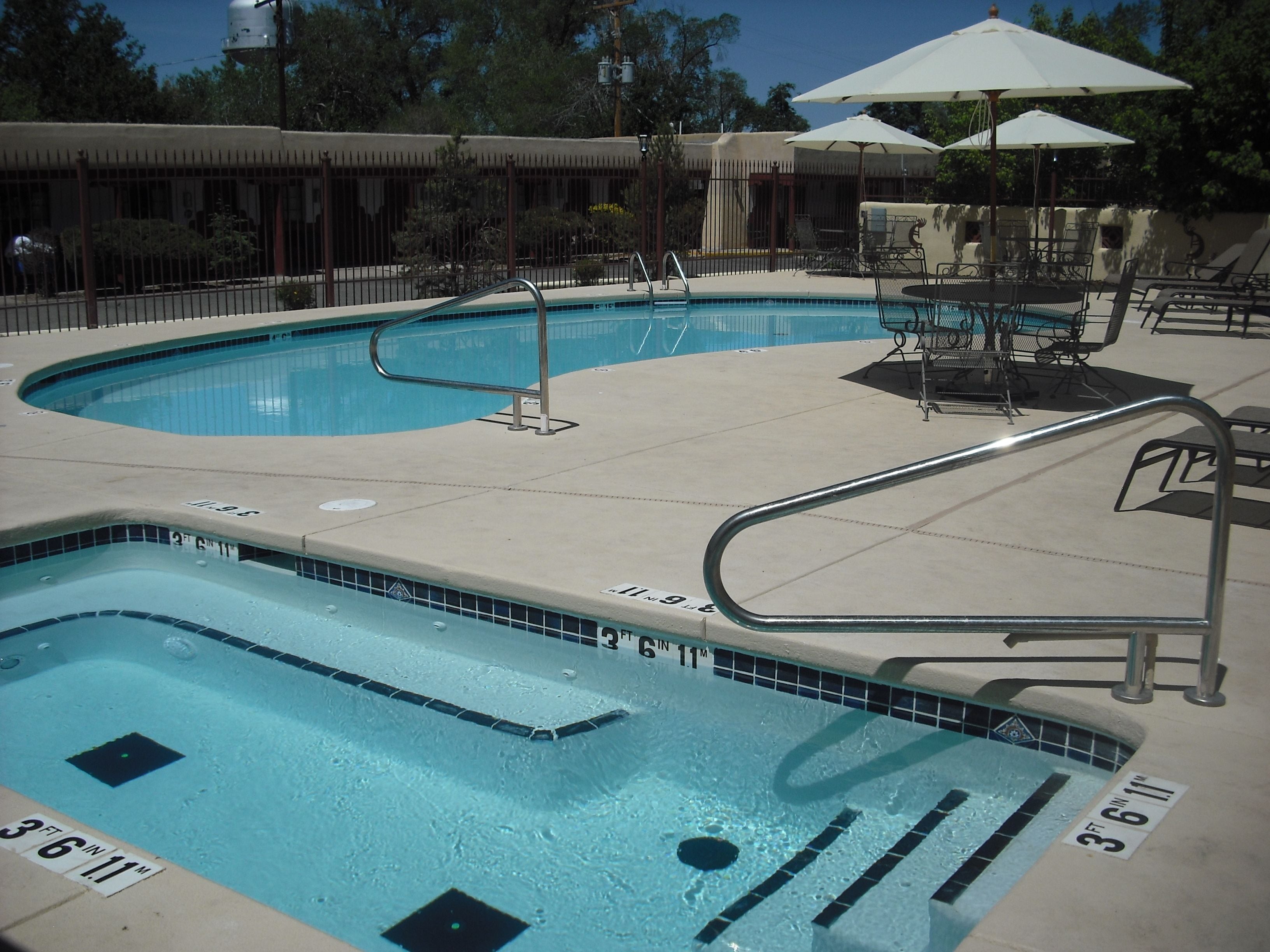 A swimming pool with a diving board, lounge chairs, and umbrellas.