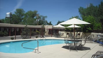 Een seizoensgebonden buitenzwembad en ligstoelen