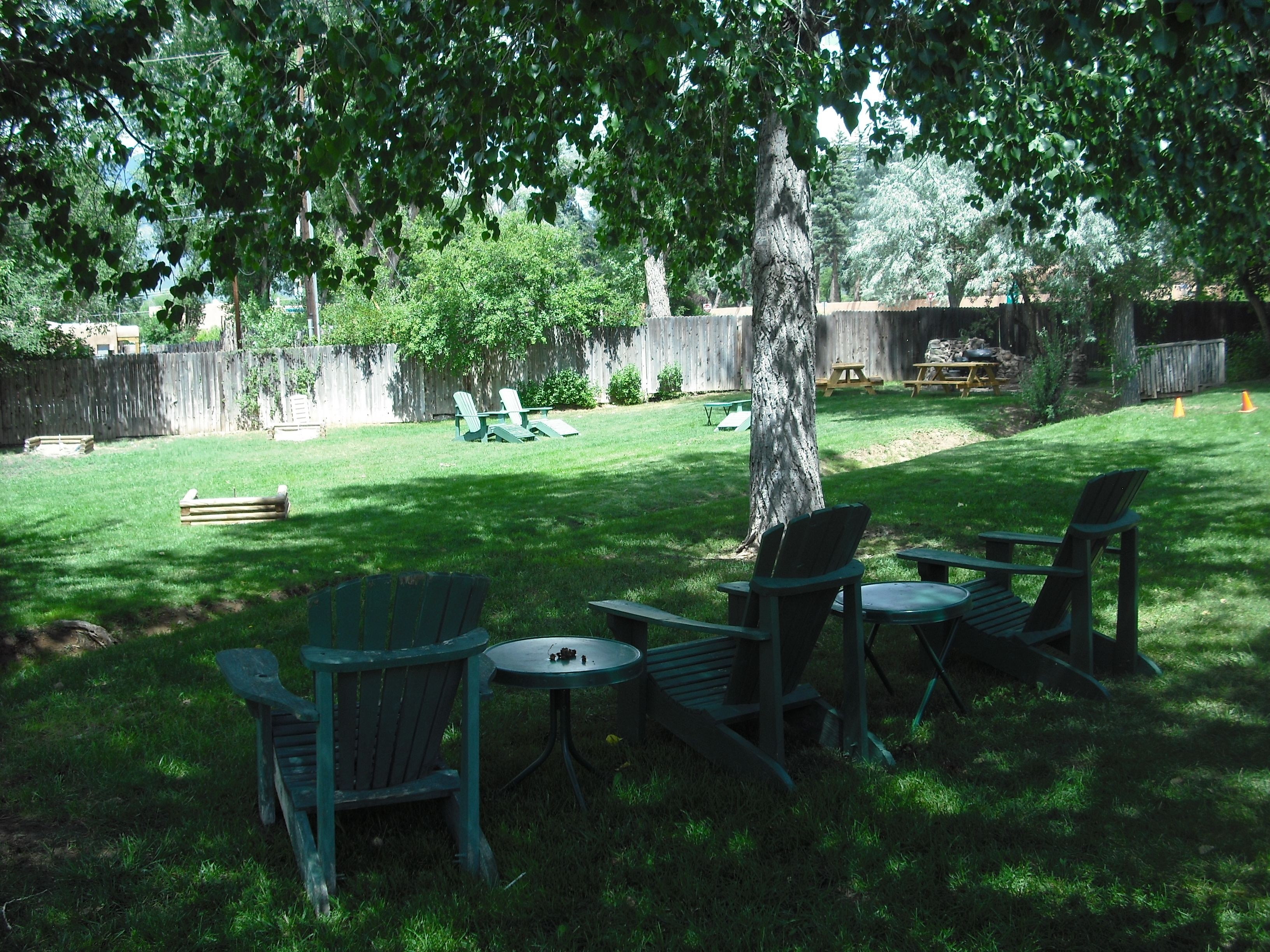 A backyard with green lawn chairs and a picnic table.
