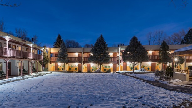 A hotel with a snow-covered courtyard, multiple balconies, and outdoor seating areas. - El Pueblo Lodge (Taos)