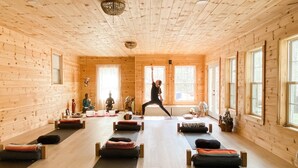 Um estúdio de yoga com paredes de madeira e grandes janelas.